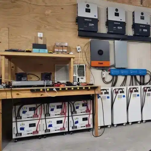 Server rack mount batteries paired with multiple hybrid inverters in a residential off-grid solar installation room.